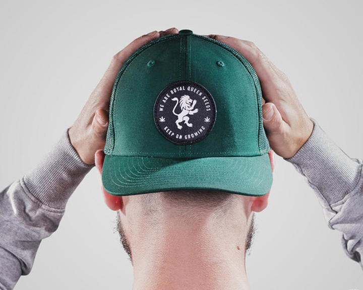 RQS Trucker Hat Una persona che tiene un berretto da baseball verde con un logo di leone bianco e le parole