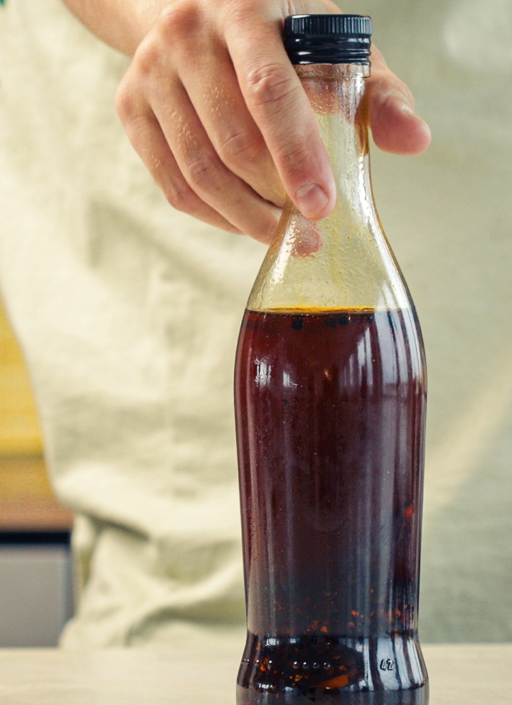 Bottiglia di vetro sigillata piena di olio al peperoncino infuso alla cannabis conservata in cucina